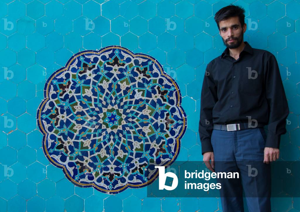 Iranian shiite man in JAmeh Mosque in front of a blue mosaic, Yazd Province, Yazd, Iran (photo)