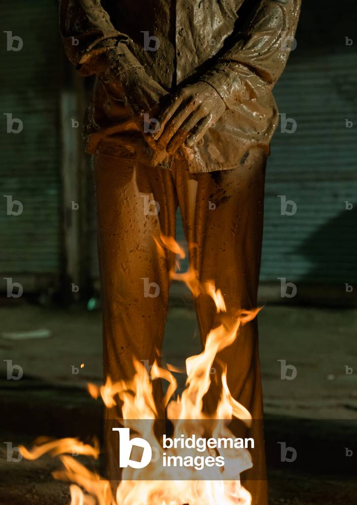 Iranian shiite muslim man standing in front of a bonfire after rubbing mud on his body during the Kharrah Mali ritual to mark the Ashura ceremony, Lorestan Province, Khorramabad, Iran (photo)