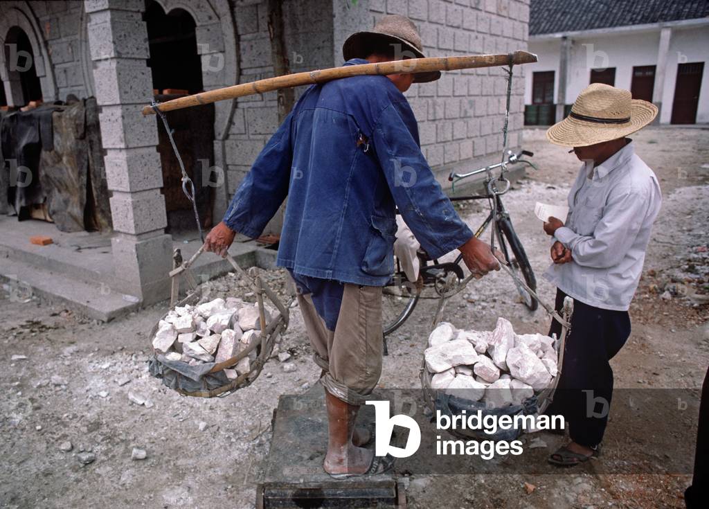 Buiding labourer being weighed carrying rubble from building site, Shaoxing, China (photo)