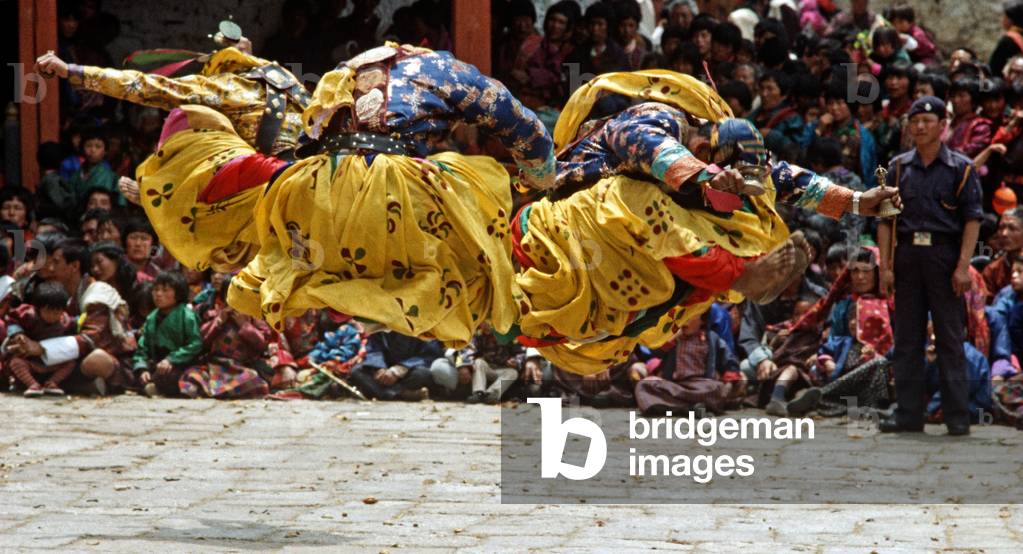 Bell dancers jumping at the Paro Tshechu, mask dance festival, in the Paro Dzong, Bhutan (photo)