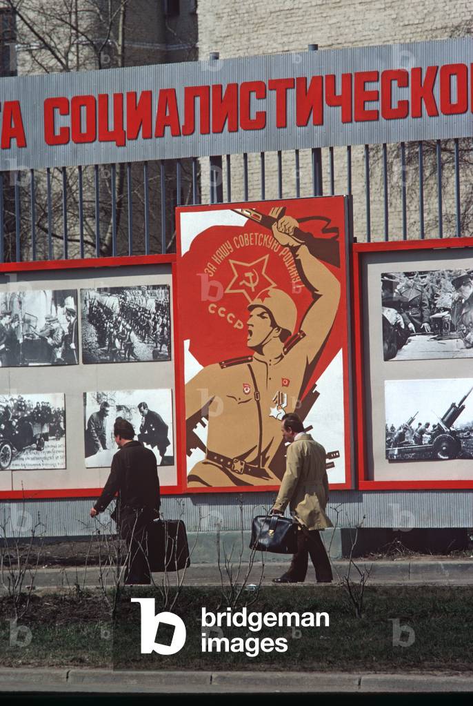 Men walking infront of Russian Army recruitment poster, Moscow, Russia (photo)