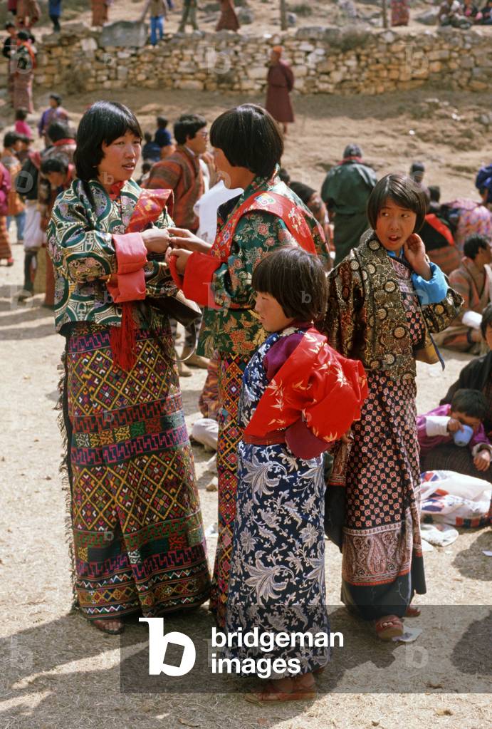 Bhutanese women and children in traditional costumes at the Paro Tshechu, mask dance festival, in the Paro Dzong, Bhutan (photo)