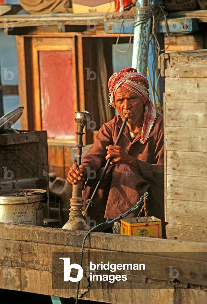 Sailor smoking water pipe on Arab Dhow, Dubai Creek, United Arab Emirates