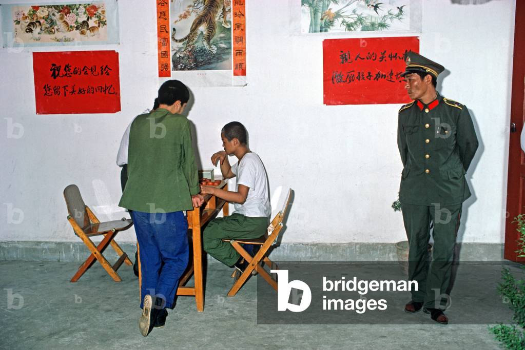 Prison guard watching over prisoners in recreation area of Chinese Youth Detention Center, Chengdu, China, 1985 (photo)