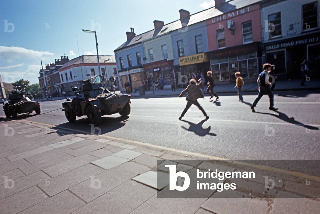 Nationalist youths throwing stones at British Army Scout Cars in West Belfast during The Troubles, Northern Ireland, 1972 (photo)