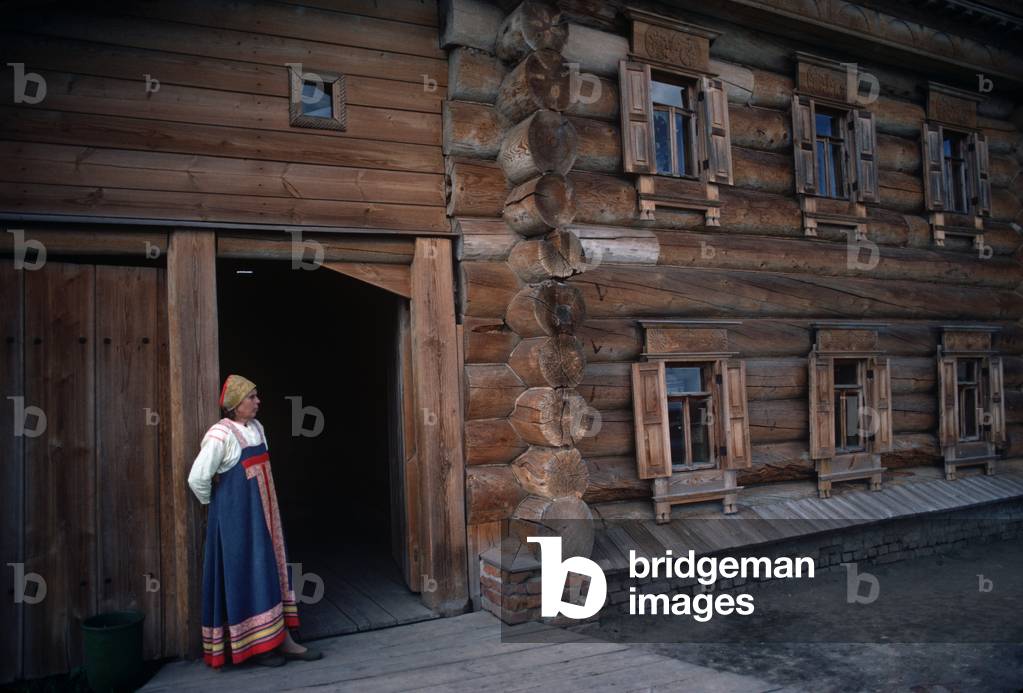 Woman in traditional costume in front of 18th Century Wooden Church, Suzdal, Russia (photo)