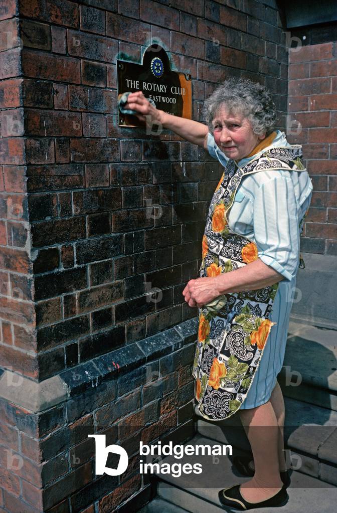 Cleaning lady polishing Rotary club name plate in Eastwood, South Nottinghamshire (photo)