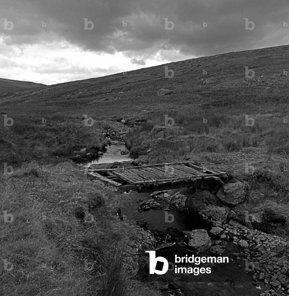 Truck chassis acting as bridge across stream in the Sperrin Mountains, Northern Ireland (b/w photo)