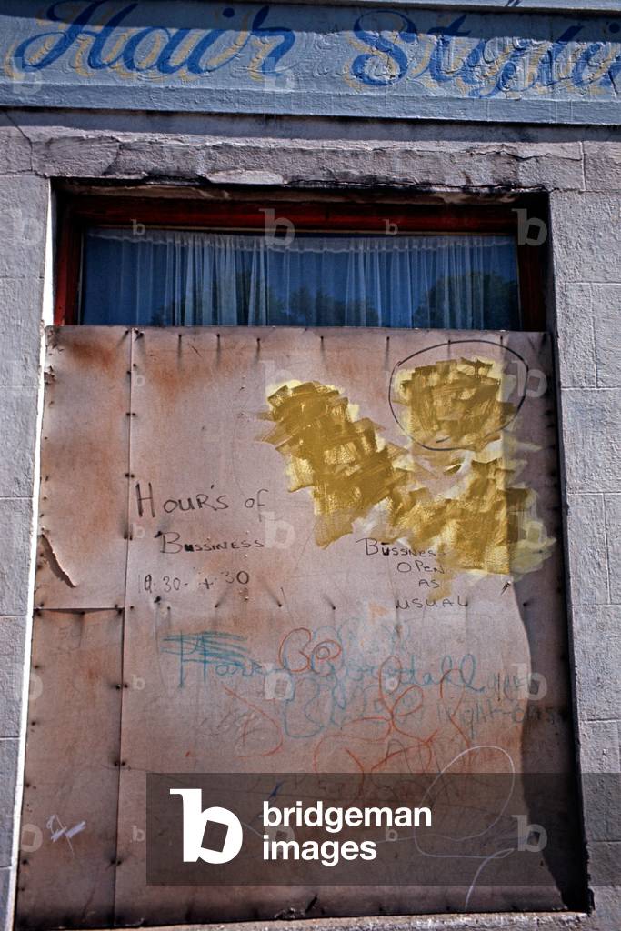Boarded up Shop Front with Business as Usual painted sign during The Troubles, Northern Ireland, 1973 (photo)
