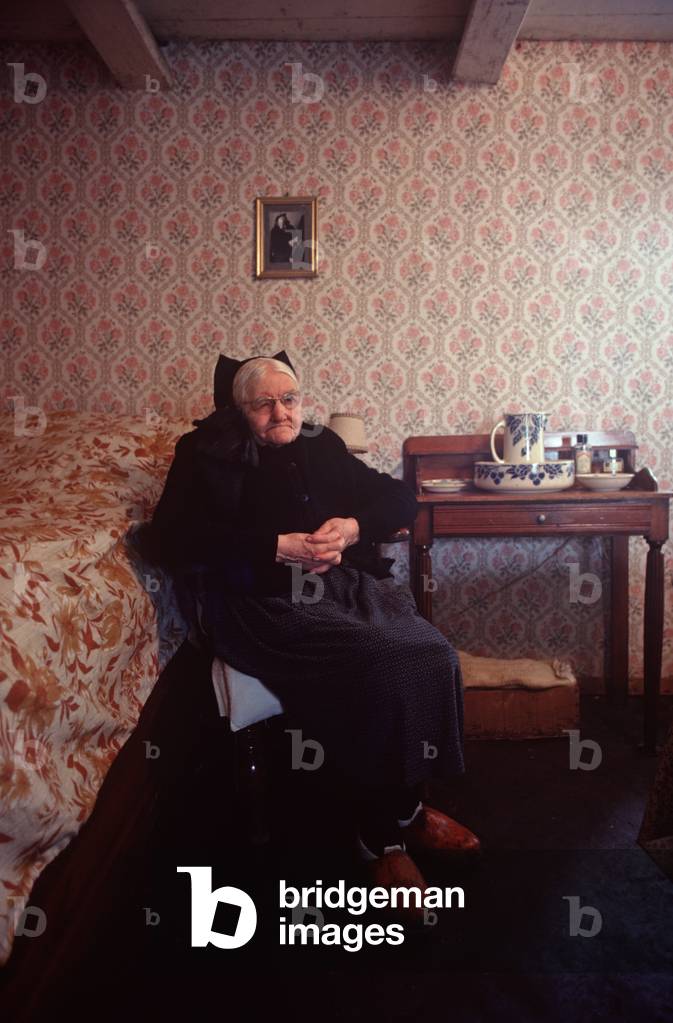 Old Breton lady sitting in armchair in Island of Ushant house, Brittany, France (photo)