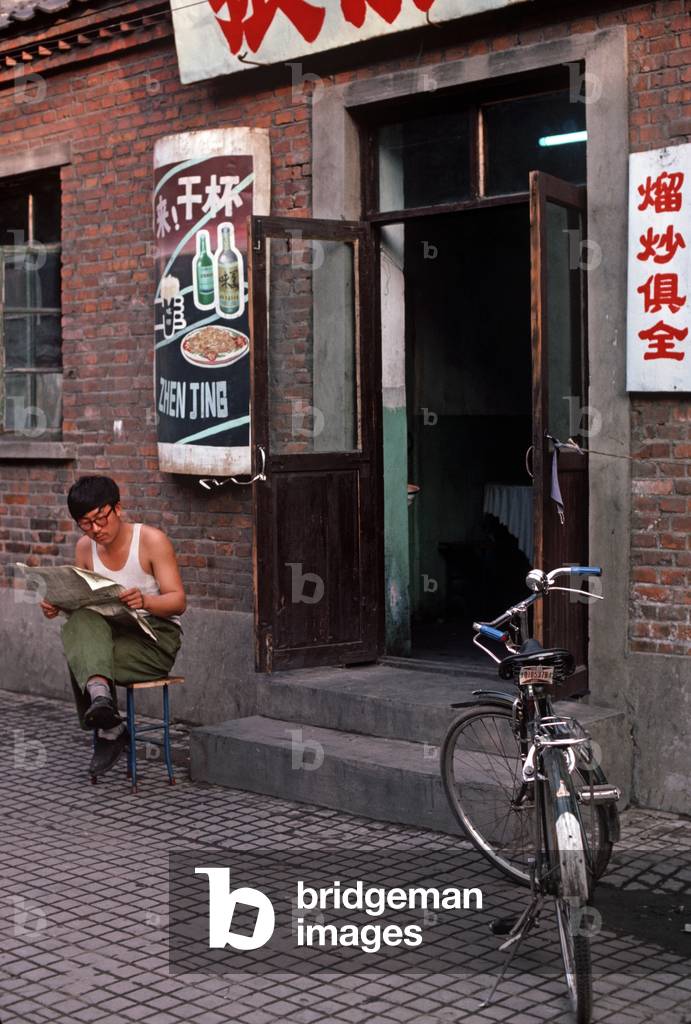 reading a newspaper in front of Harbin restaurant, Heilongjiang Province, China (photo)