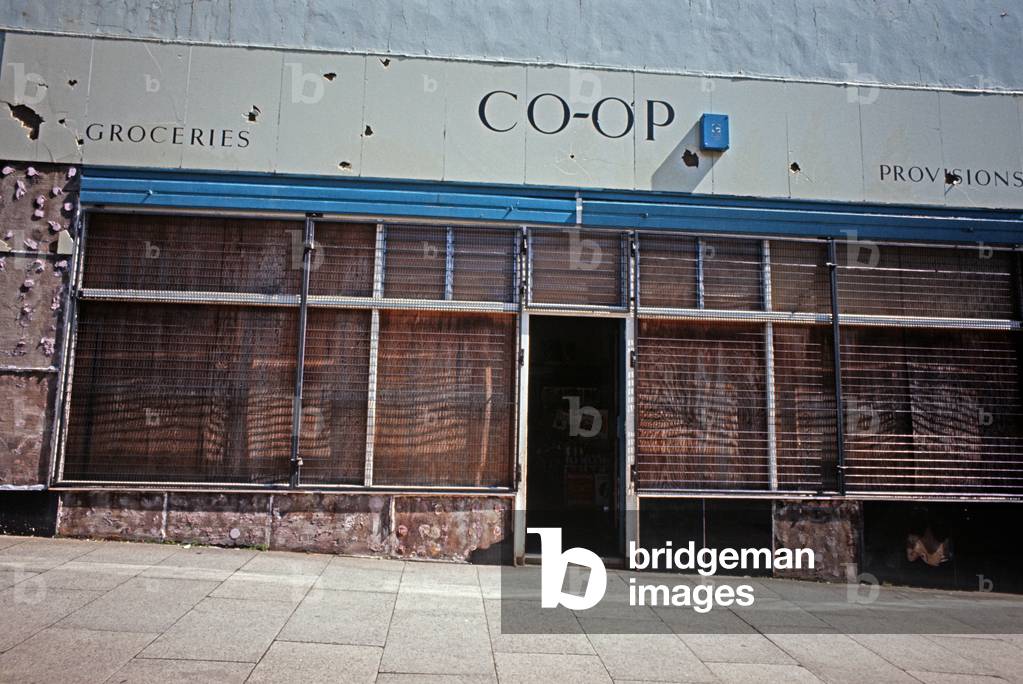 Boarded up Shop Front with Business as Usual painted sign during The Troubles, Northern Ireland, 1973 (photo)