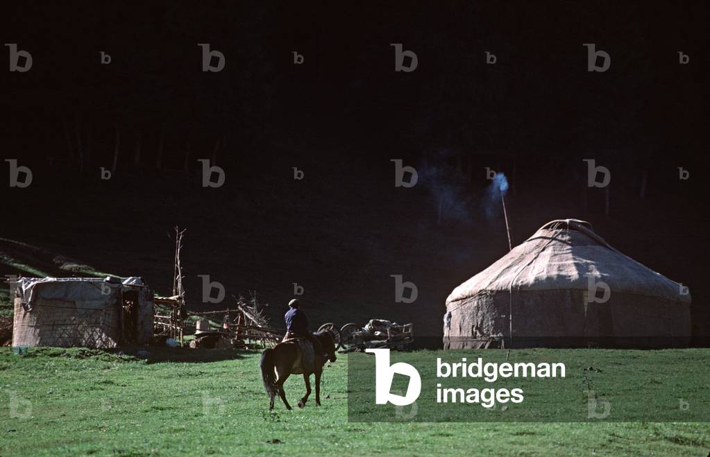Kazakh horseman riding into Yurt settlement in hills North of Urumqi, Xinjiang Province, China (photo)