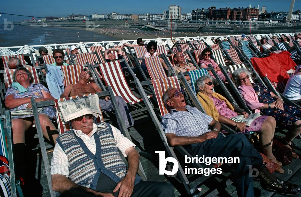 August Bank holiday makers sunbathing in deckchairs on Blackpool North Pier, Lancashire (photo)