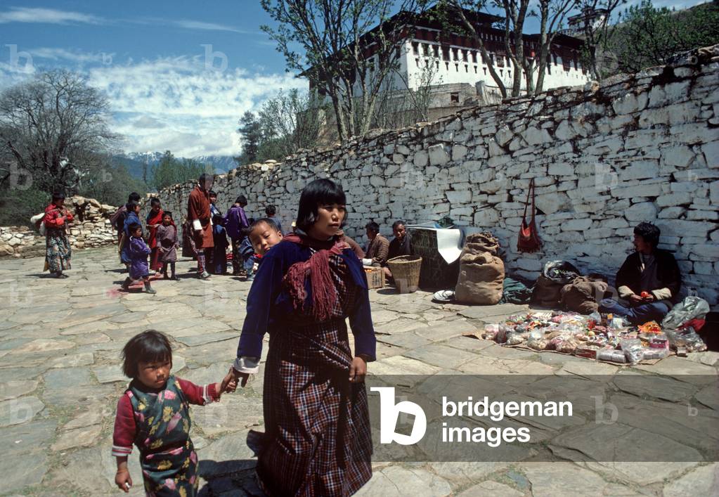 Mother and child and market traders in front of Paro Dzong, Buddhist monastery, Bhutan, Himalayas (photo)
