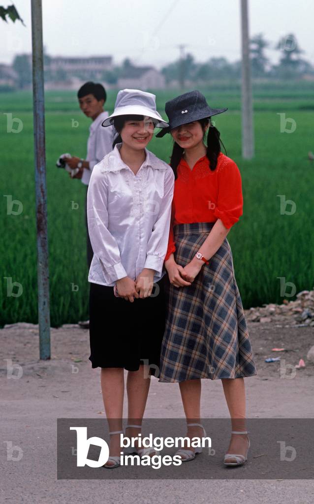 Two young Chinese girls with hats waiting for bus in Shaoxing, China (photo)