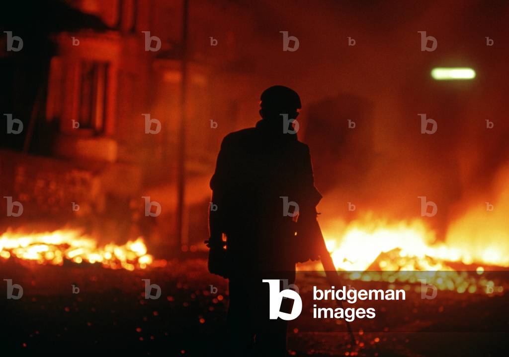 British Army Soldier standing in front of burning barricade during The Troubles in Belfast, Northern Ireland, 1976 (photo)