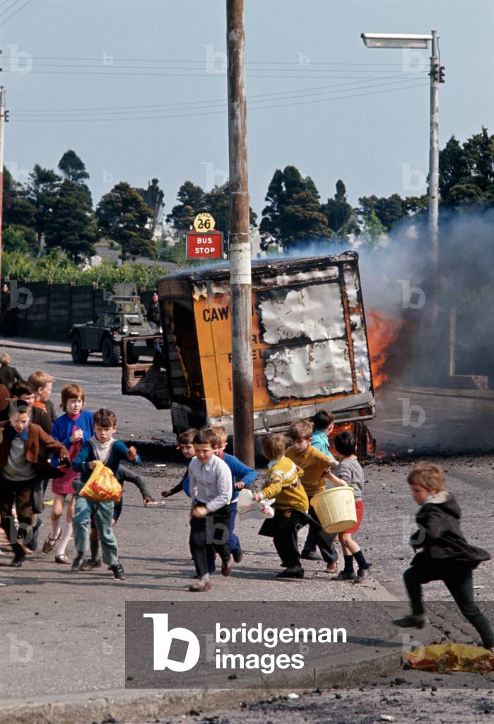 Children running away from burning hijacked vehicle in West Belfast during The Troubles, 1972 (photo)
