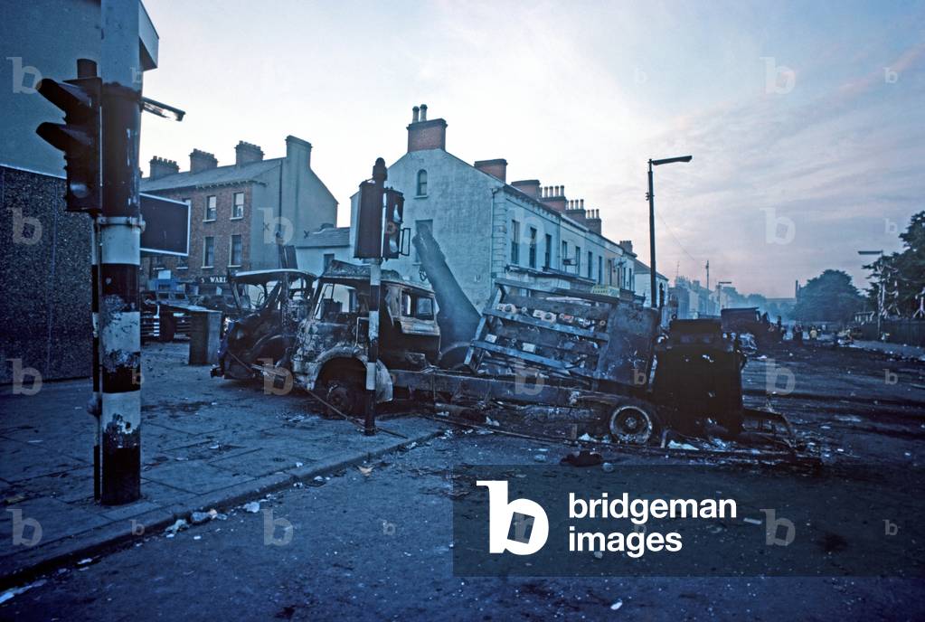 Burnt out Hijacked Vehicles on the Falls Road, West Belfast after a Night of Rioting during The Troubles, Northern Ireland, 1976 (photo)
