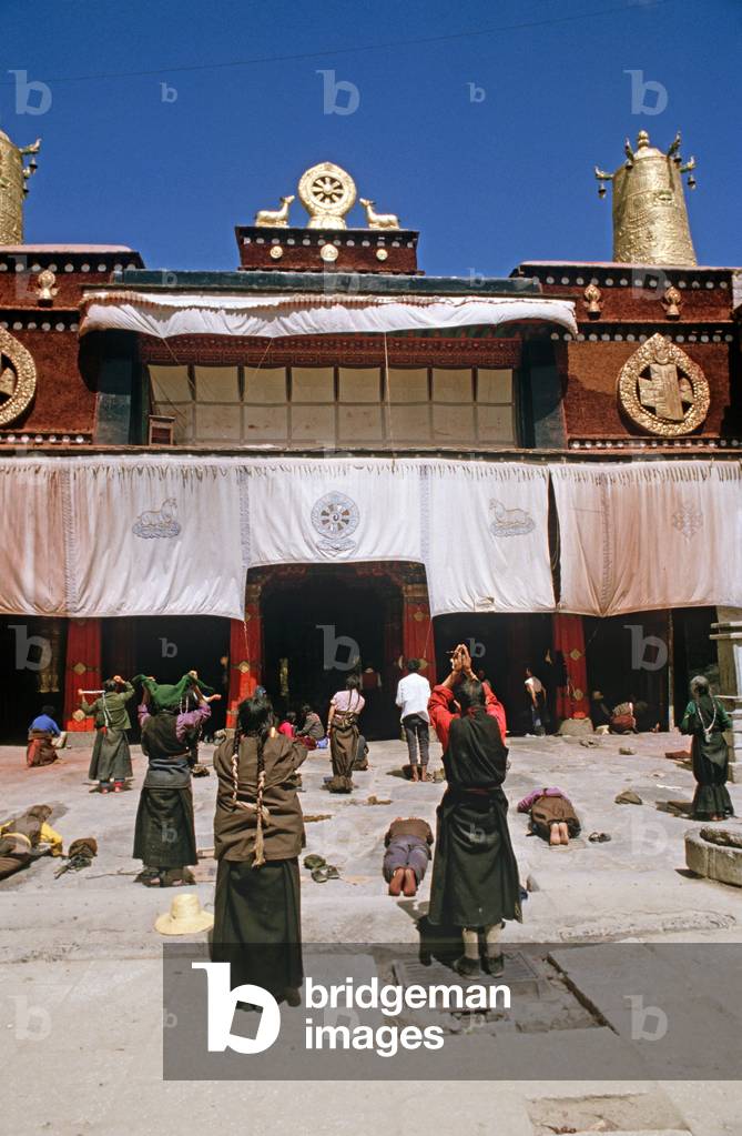 Buddhist pilgrims prostrating themselves in front of Jokhang Temple, Lhasa, Tibet (photo)
