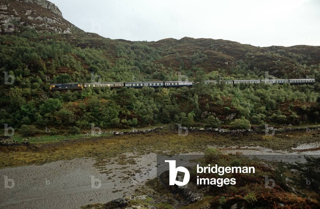 British Rail diesel train on the Kyle of Lochalsh line running alongside Loch Carron, North West of Coast Scotland, 1982 (photograph)