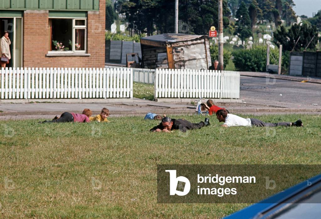 People sheltering on the ground during an IRA Sniper attack on the British Army in West Belfast during The Troubles, Northern Ireland, 1972 (photo)