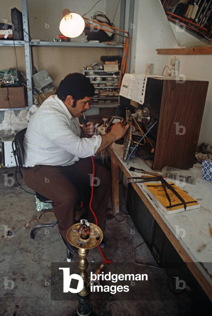 Palestinian TV repair man smoking tobacco through a pipe, West Bank, East Jerusalem,  Israeli, Palestinian Authority (photo)