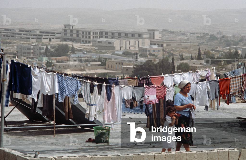Palestinian woman and child hanging out washing to dry on rooftop in West bank, East Jerusalem, Israeli, Palestinian Authority (photo)