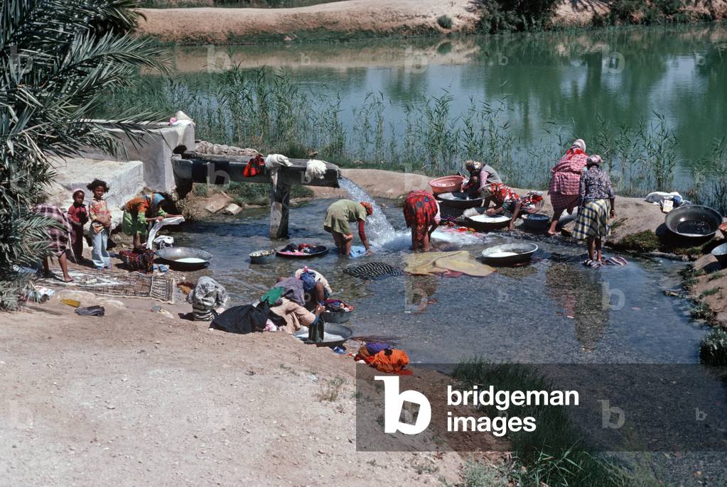 Arab Berger women and children in Tozeur oasis hand washing clothes, Sahara desert, South Tunisia, North Africa (photo)