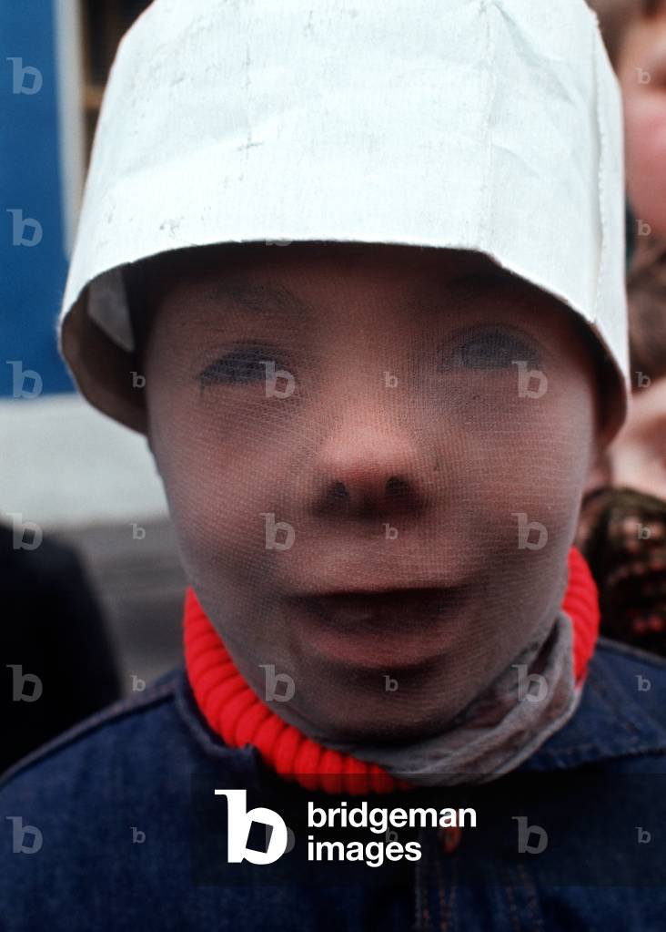 Boy playing at being a masked Ulster Defence Association paramilitary man in Protestant part of Belfast during The Troubles, Northern Ireland, Ulster, 1974