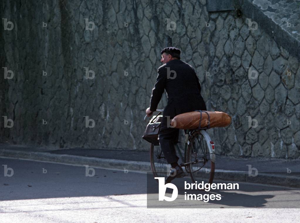 Cyclist with beret and loaf of bread in town of St-Sauveur-Le-Vicomte, Normandy, France (photo)