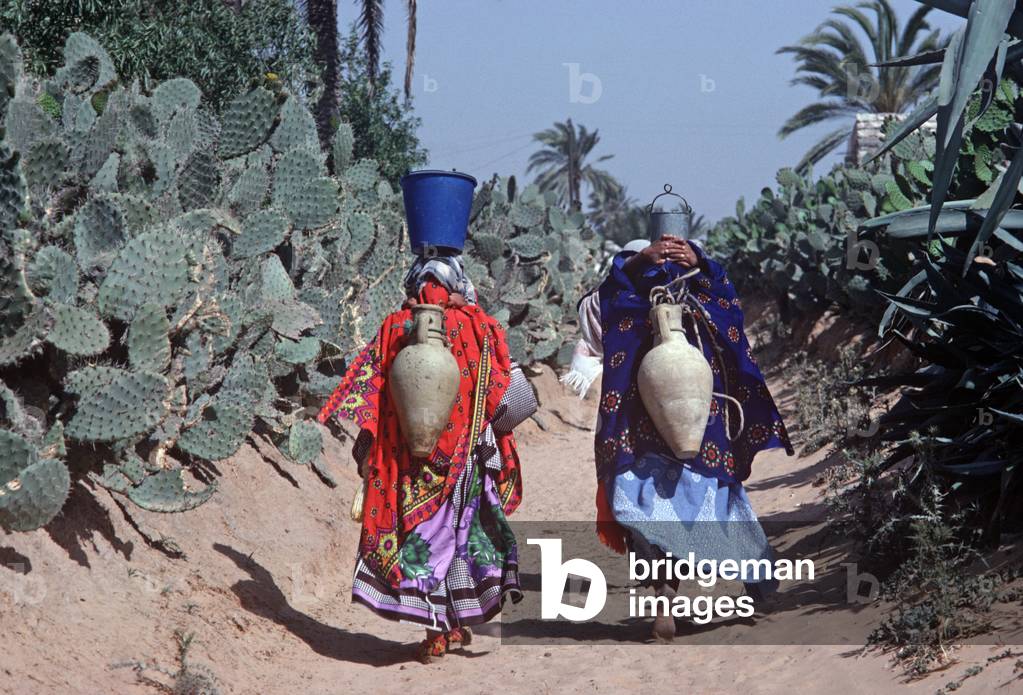 Tunisian Arab Berber women on their way to the Tozeur oasis to collect water in their amphora clay vessels  (photo)