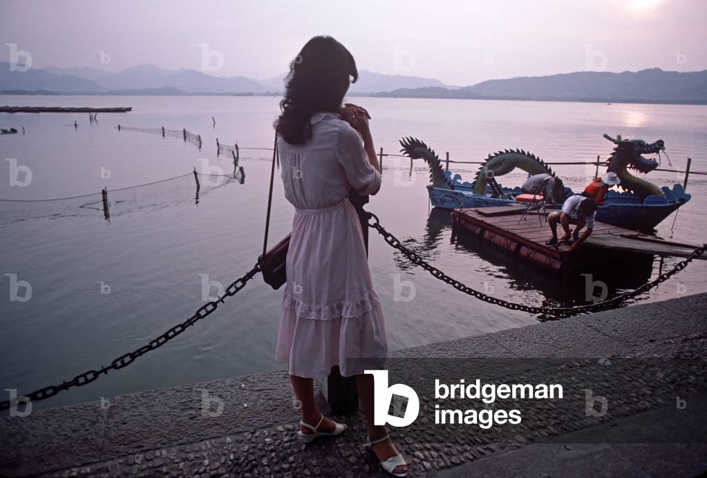 Young woman watching sun setting on dragon tourist boat on West Lake, Hangzhou, Zhejiang Province, China (photo)