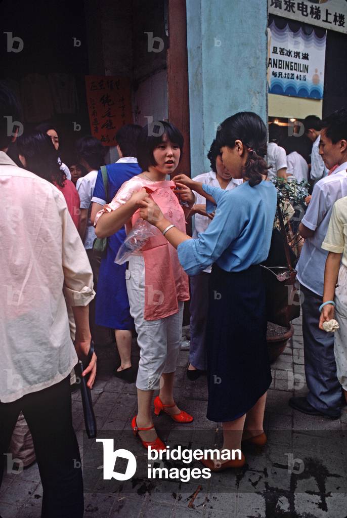 Chinese woman trying out clothes in Chengdu market, Sichuan, China (photo)
