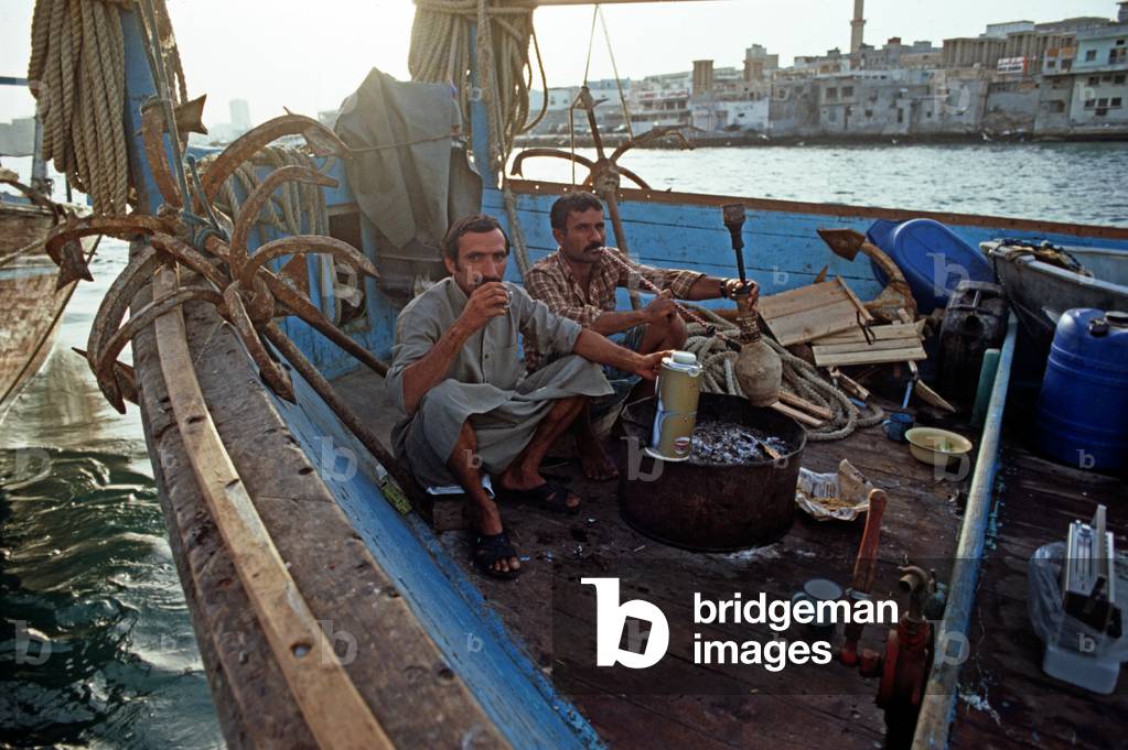 Sailors smoking water pipe on motorised Arab dhow, Dubai Creek, United Arab Emirates