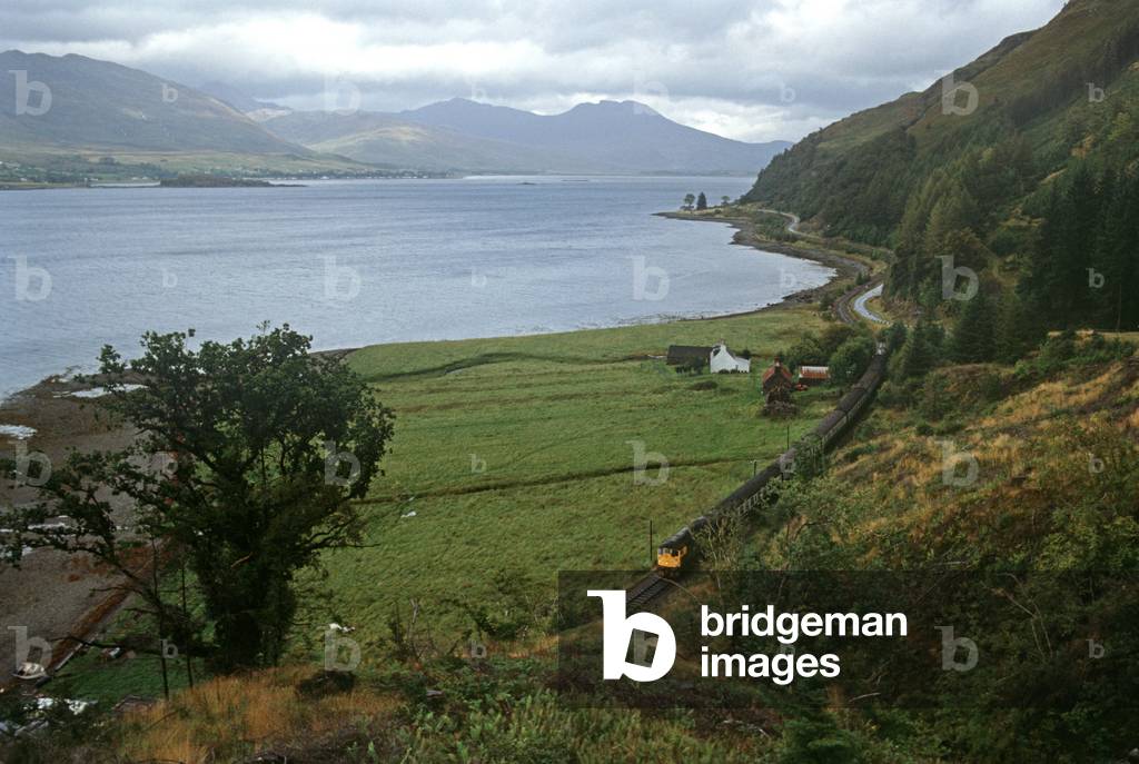 British Rail diesel train on the Kyle of Lochalsh line running alongside Loch Carron, North West Coast of Scotland, 1982 (photograph)