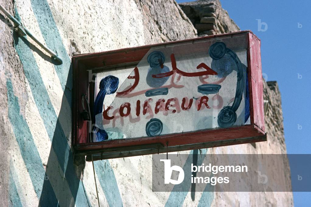 Hand painted hairdresser broken sign in South Tunisia town (photo)