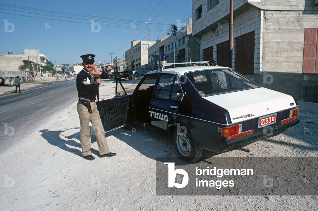 Palestinian policeman with police car on West Bank, East Jerusalem, Israeli, Palestinian Authority (photo)