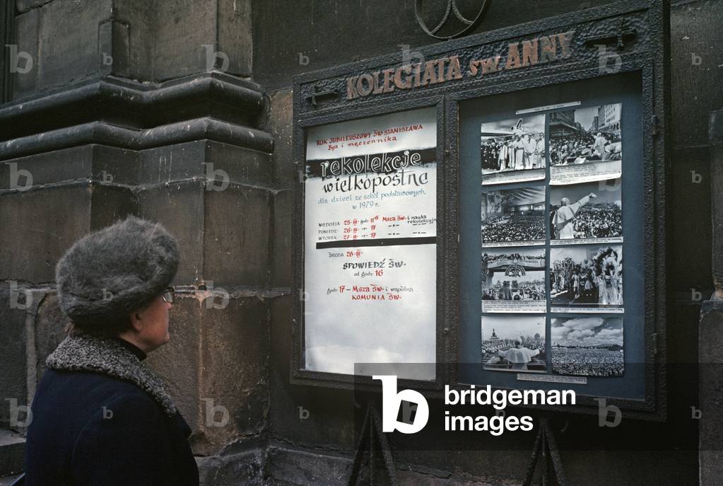 Woman looking at photos of Pope John Paul on message board in Cracow, Poland, 1979 (photo)
