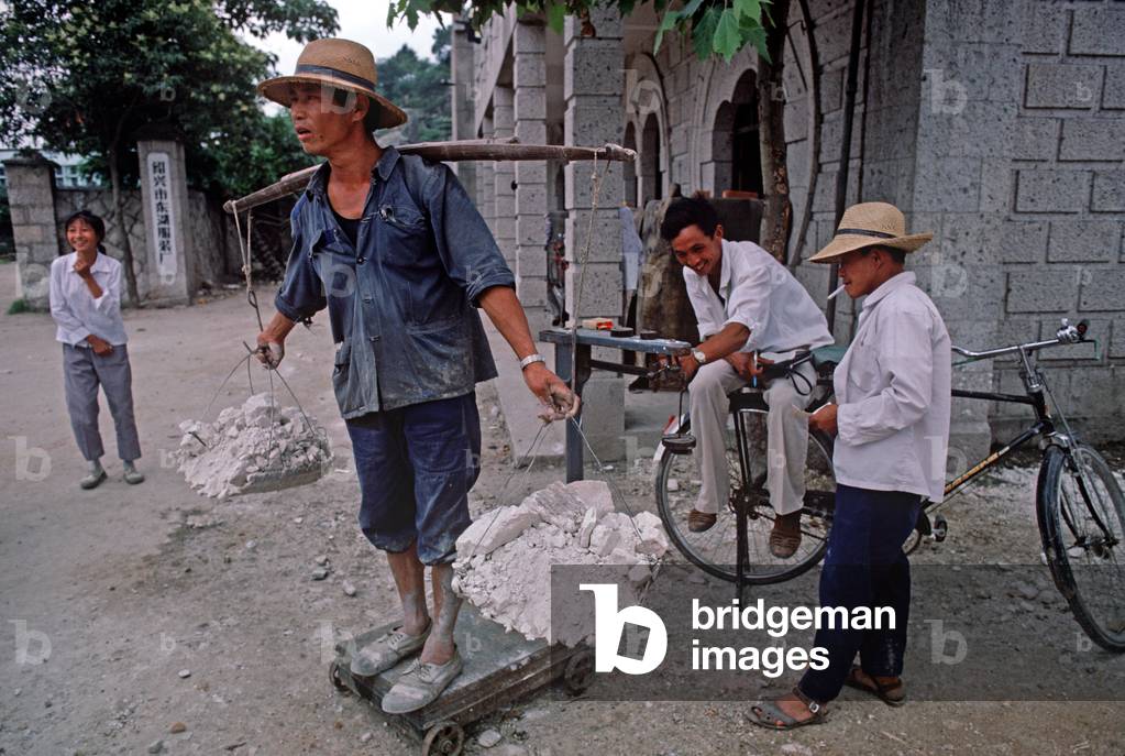 Buiding labourer being weighed carrying rubble from building site, Shaoxing, China (photo)