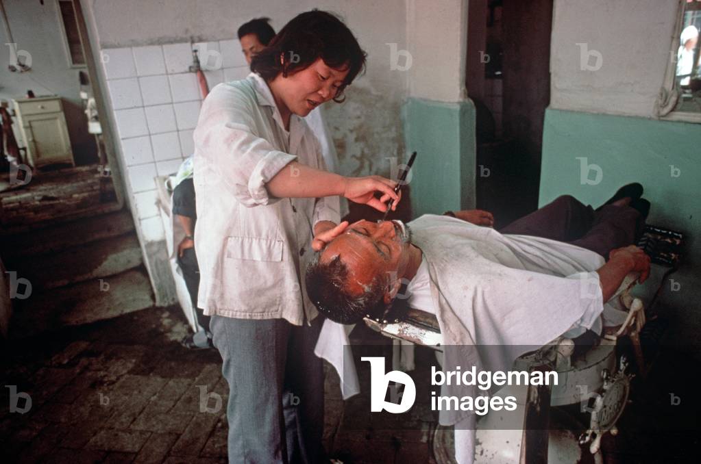 woman barber shaving man in barber shop, Shaoxing, China (photo)
