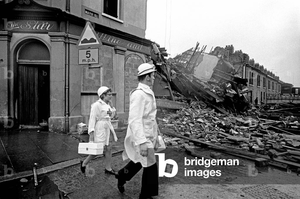 Red Cross workers inspecting IRA bomb damage in the Shankill area of Belfast, Northern Ireland in the 70s during The Troubles, 1976 (b/w photo)
