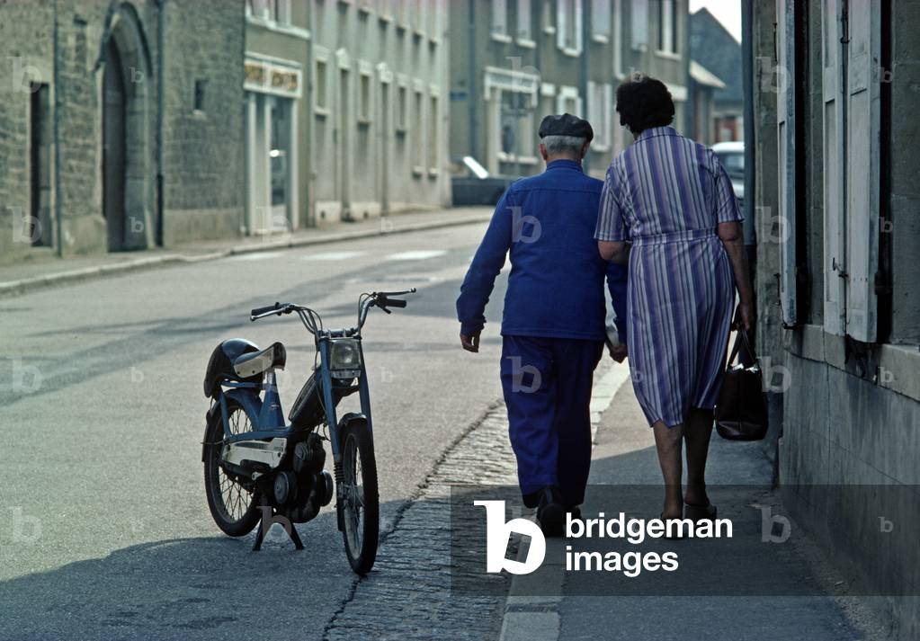 Couple walking in street of town of St-Sauveur-Le-Vicomte, Normandy, France (photo)