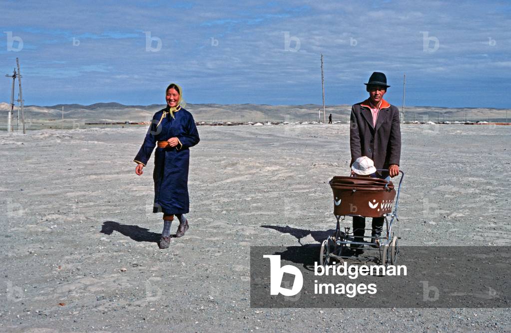 Mongolian couple and baby in pram walking in Gobi-Altai town, Gobi-Altai Province, Monglia, Asia