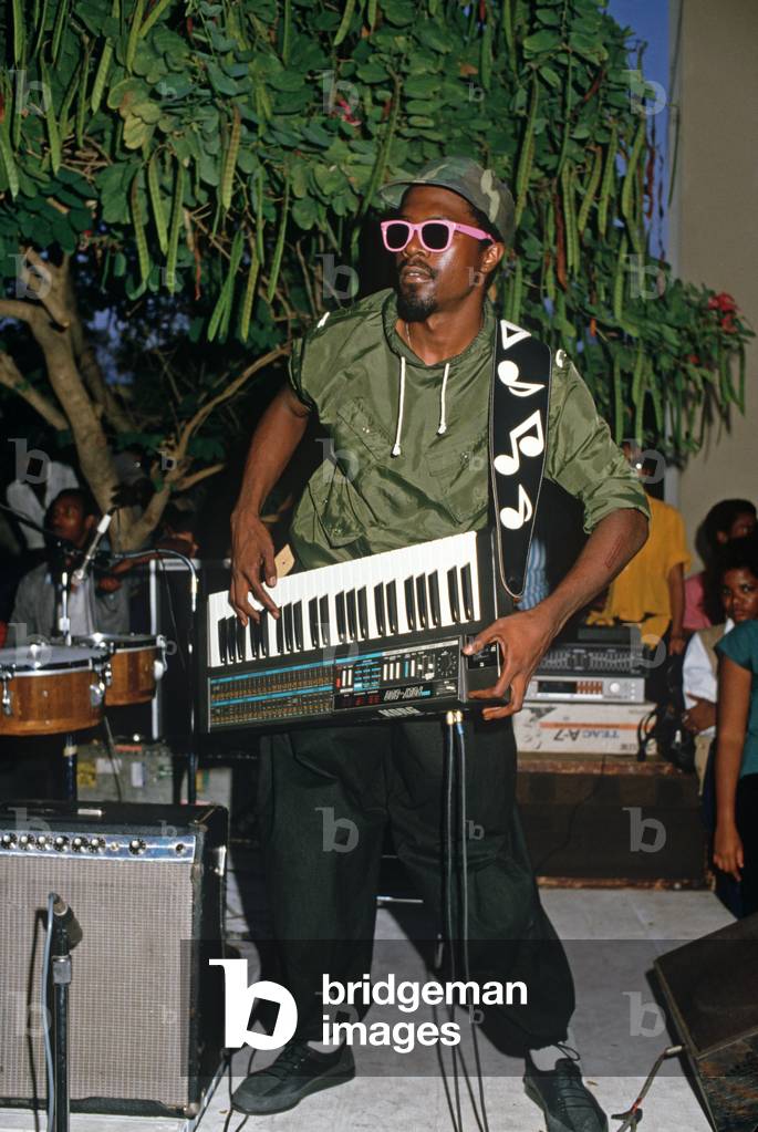 Member of The Blood Fire Posse with his mobile keyboard synthesizer playing reggae at Kingston Kigh School concert, Kingston, Jamaica (photo)