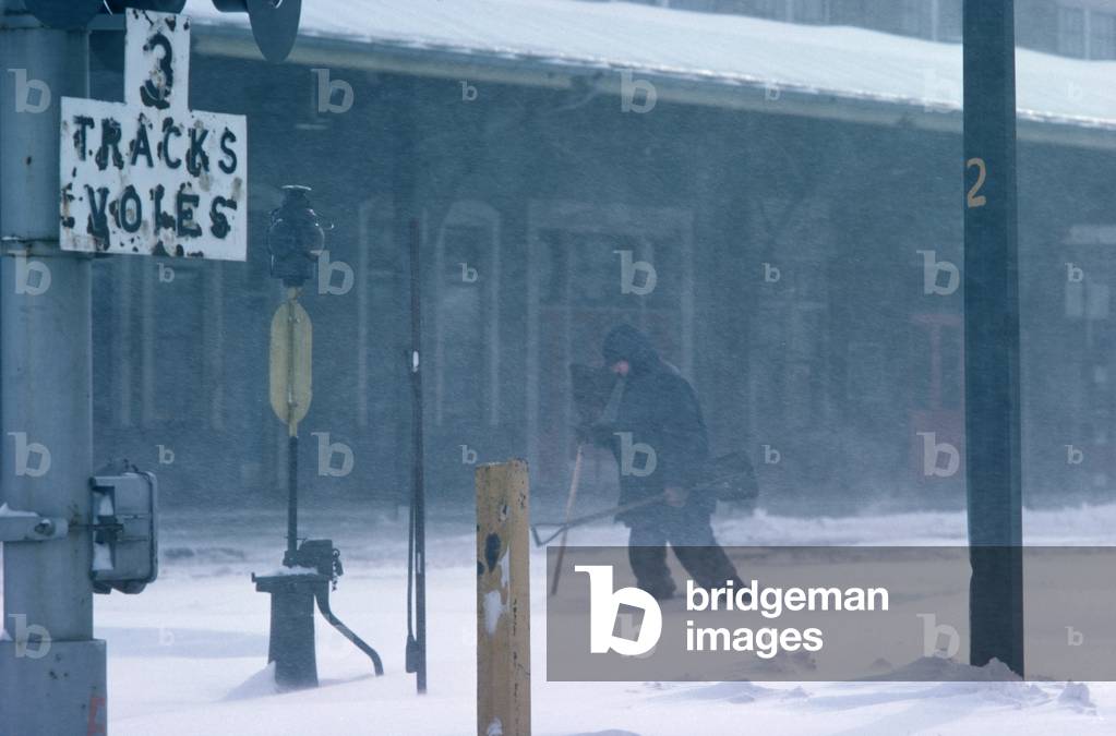 Railway worker with snow shovel to clear snow away from Quebec railway station, Quebec Province, Canada (photo)