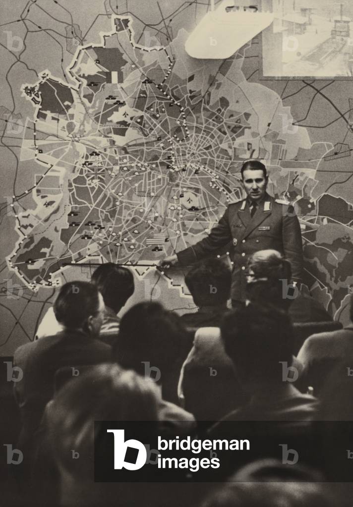 An officer of the National People's Armed Forces explains to foreign visitors at the Brandenburg Gate the necessity of the antifascist protective wall .... (b/w photo)