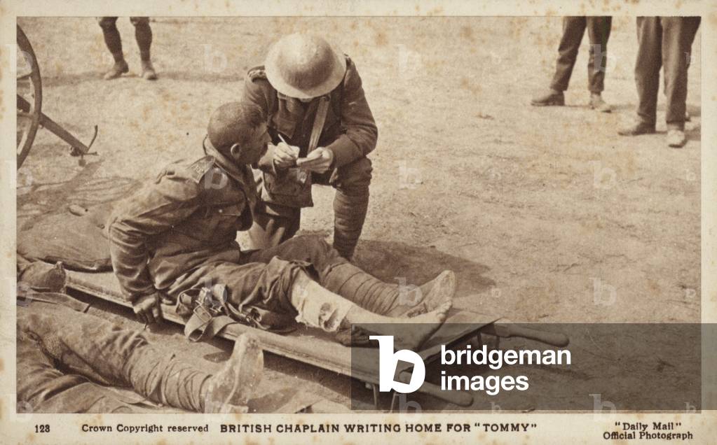 A British Army chaplain writing a letter home for a wounded soldier, World War I (b/w photo)