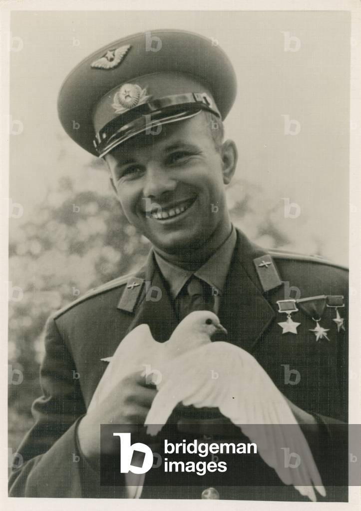 Soviet cosmonaut Yuri Gagarin holding the symbol of peace, a white dove, 1960s (b/w photo)