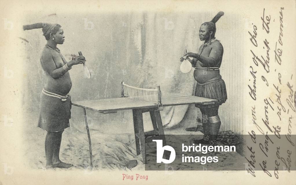 Postcard depicting two women in tribal dress playing table tennis (b/w photo)